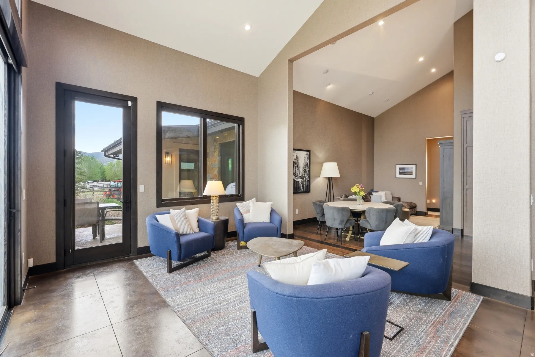 Spacious interior featuring soaring vaulted ceilings, large dark-framed windows, and expansive tiled flooring