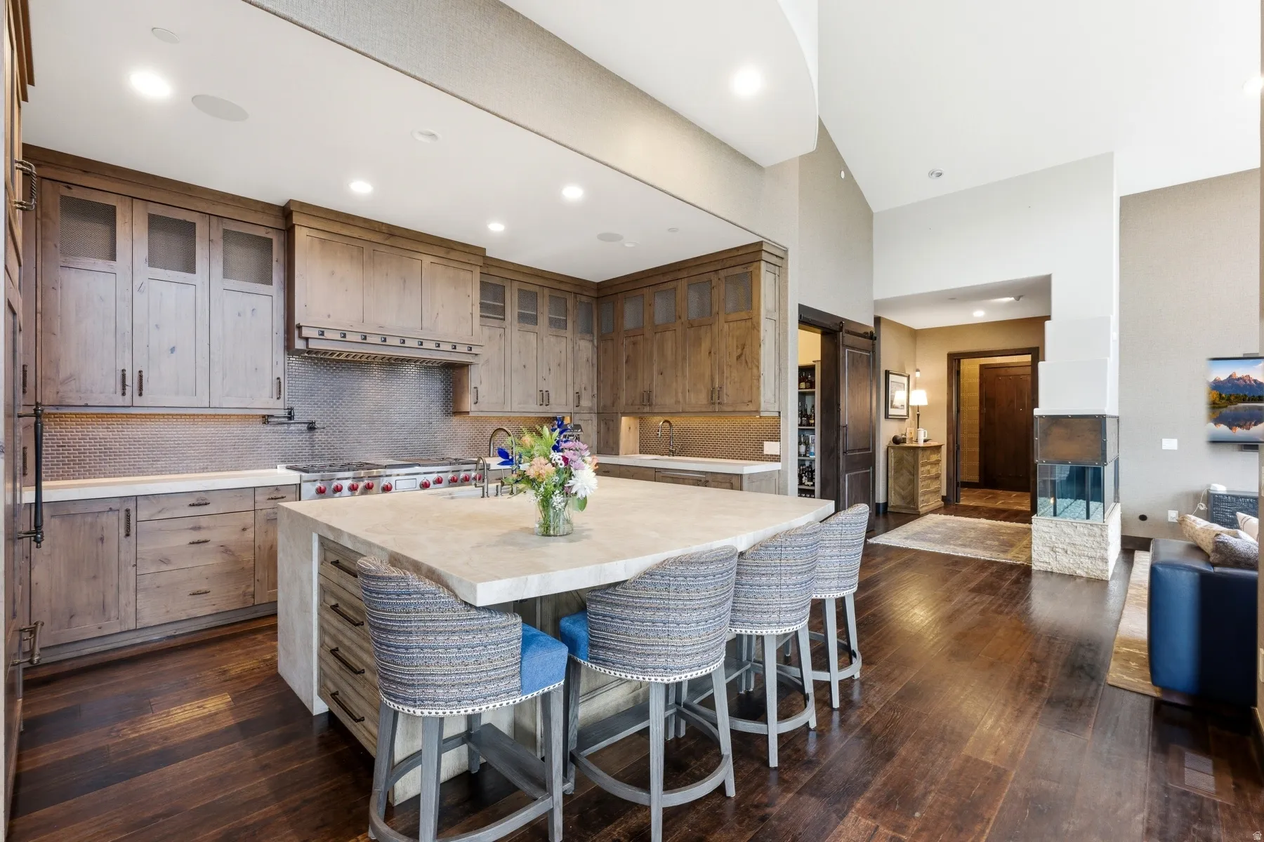 Gourmet kitchen featuring a substantial center island with seating, a professional-grade range, custom wood cabinetry, and a full-height tile backsplash