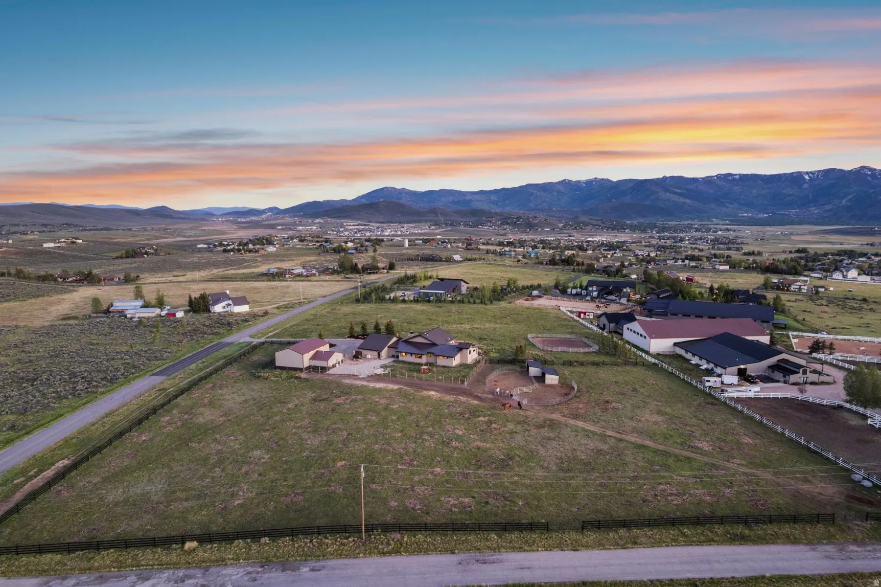 Expansive property featuring multiple structures, open fields, and mountain scenery