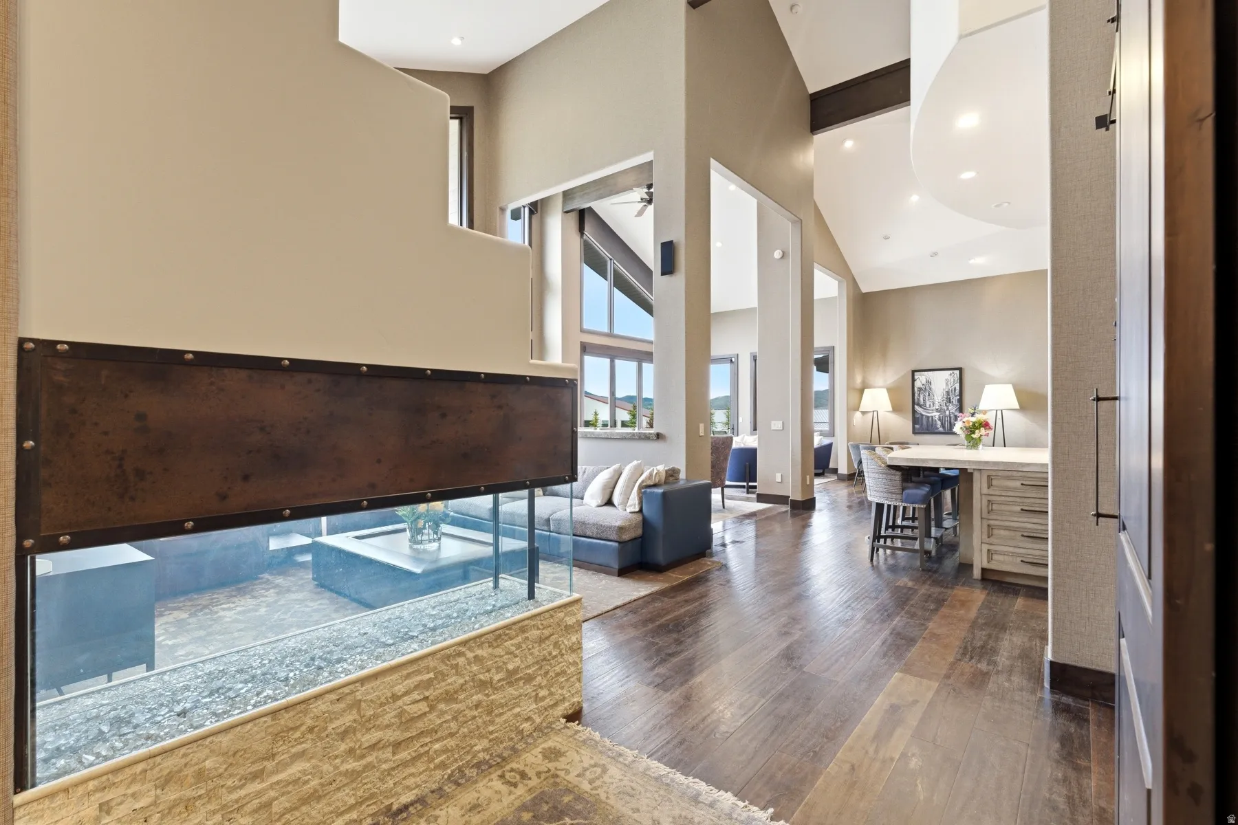Open-concept living space featuring wood-finish flooring, vaulted ceilings, and large windows