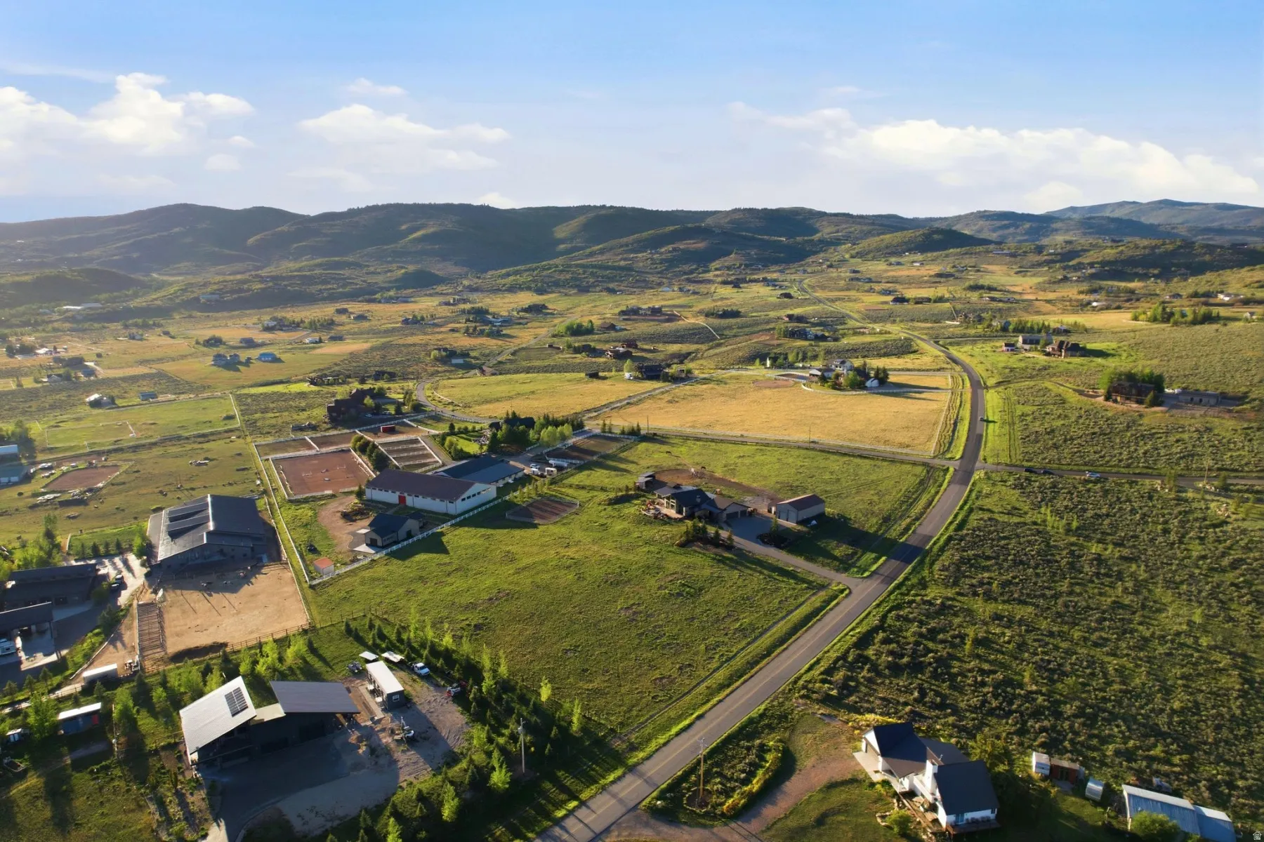 Expansive rural landscape featuring multiple properties, paved roadways, and distant mountains