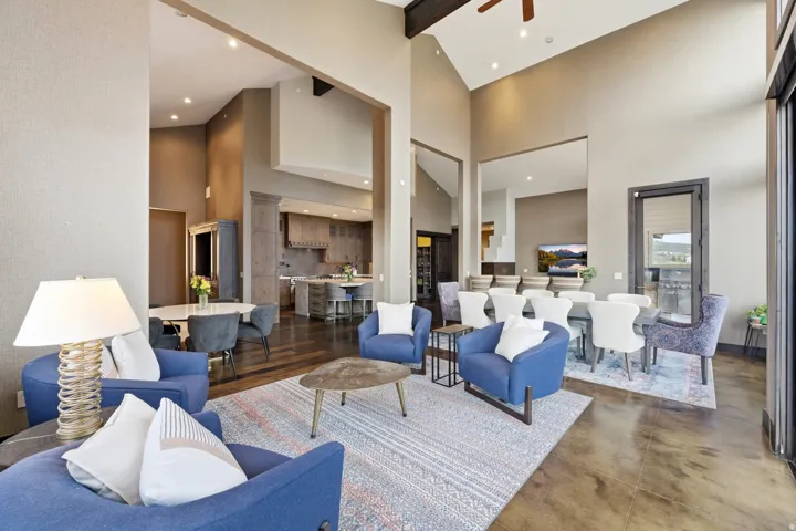 Vaulted ceilings with exposed beams, recessed lighting, expansive glass doors, wood-finish flooring, and a kitchen with an island