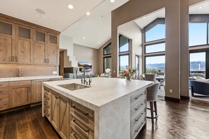 Expansive kitchen island with an integrated stainless steel sink and industrial-style faucet, complemented by wood-finish flooring