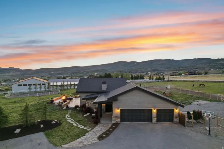 Modern-style home featuring a two-car garage with carriage-style doors, stone and siding exterior, and an expansive stone patio with built-in seating