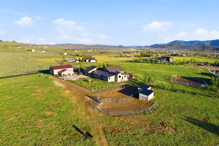Expansive property featuring multiple structures, including a primary residence, a large barn with a red roof, and smaller outbuildings