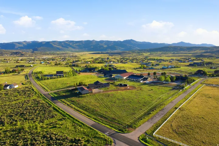 Expansive property featuring verdant green fields, multiple structures, and paved roads