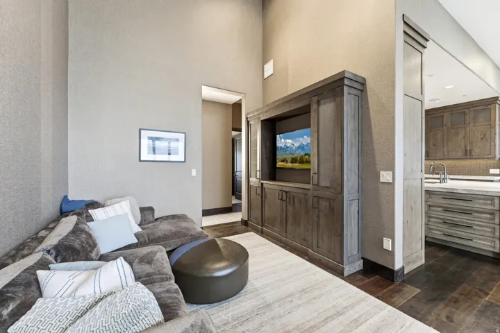 Living area featuring a custom built-in entertainment center, high ceilings, textured wall coverings, and dark wood-finish flooring