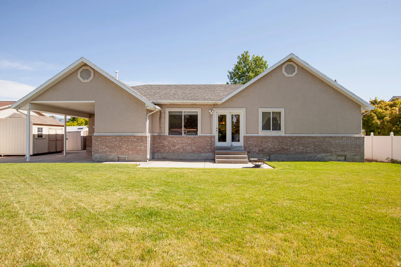 Expansive backyard with a manicured lawn, a concrete patio, and a carport