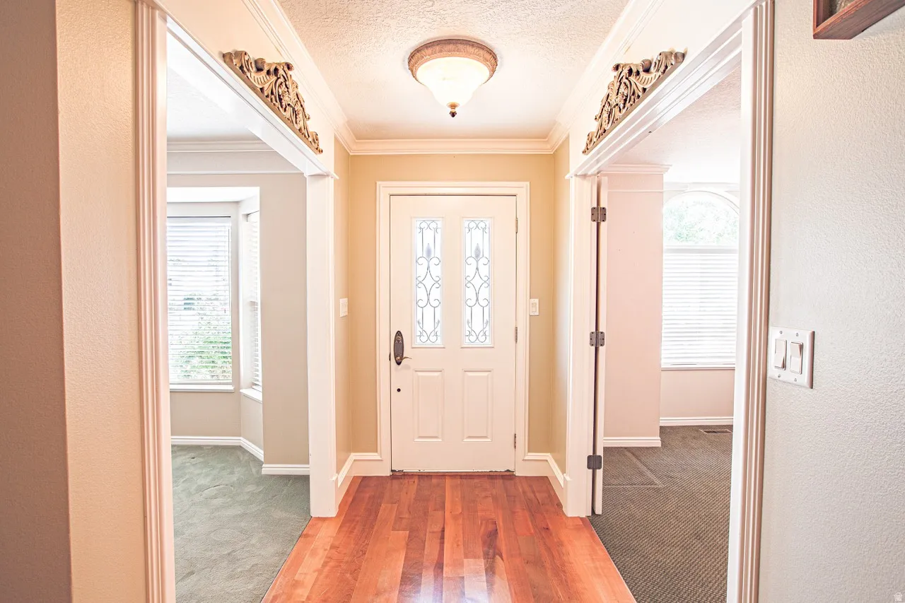 Entryway featuring wood-finish flooring, a decorative overhead light fixture, and crown molding