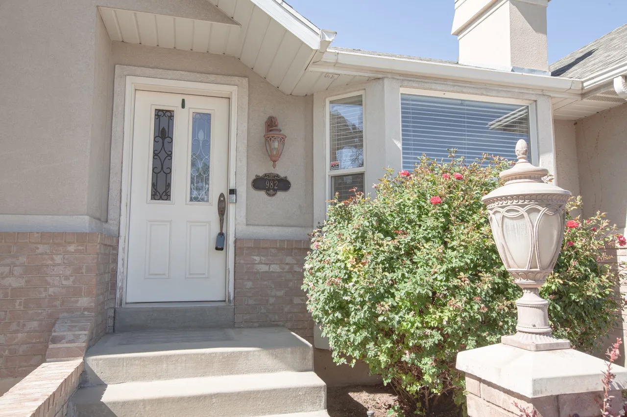 White paneled entry door with decorative glass inserts, framed by a stucco exterior and brick wainscoting