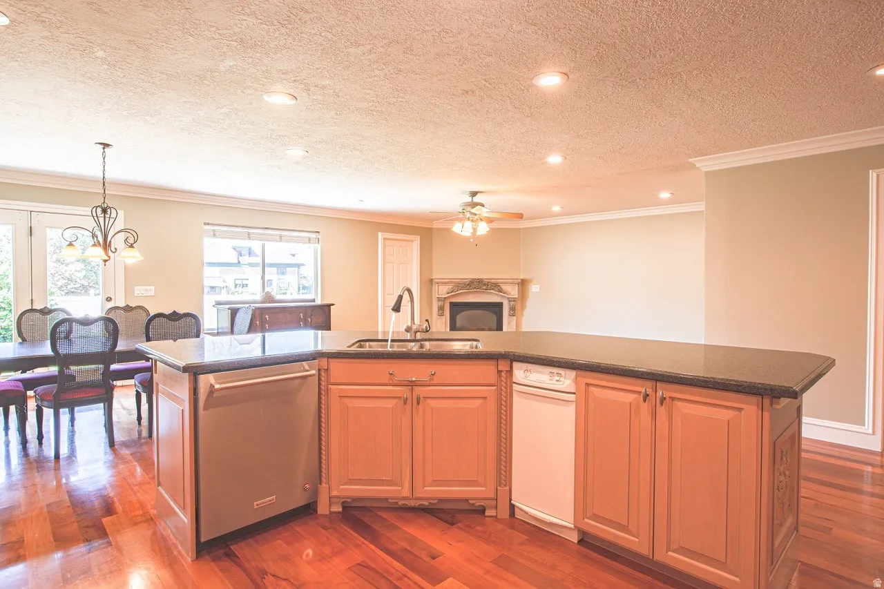 Kitchen island with integrated sink, black countertop, and light wood cabinetry