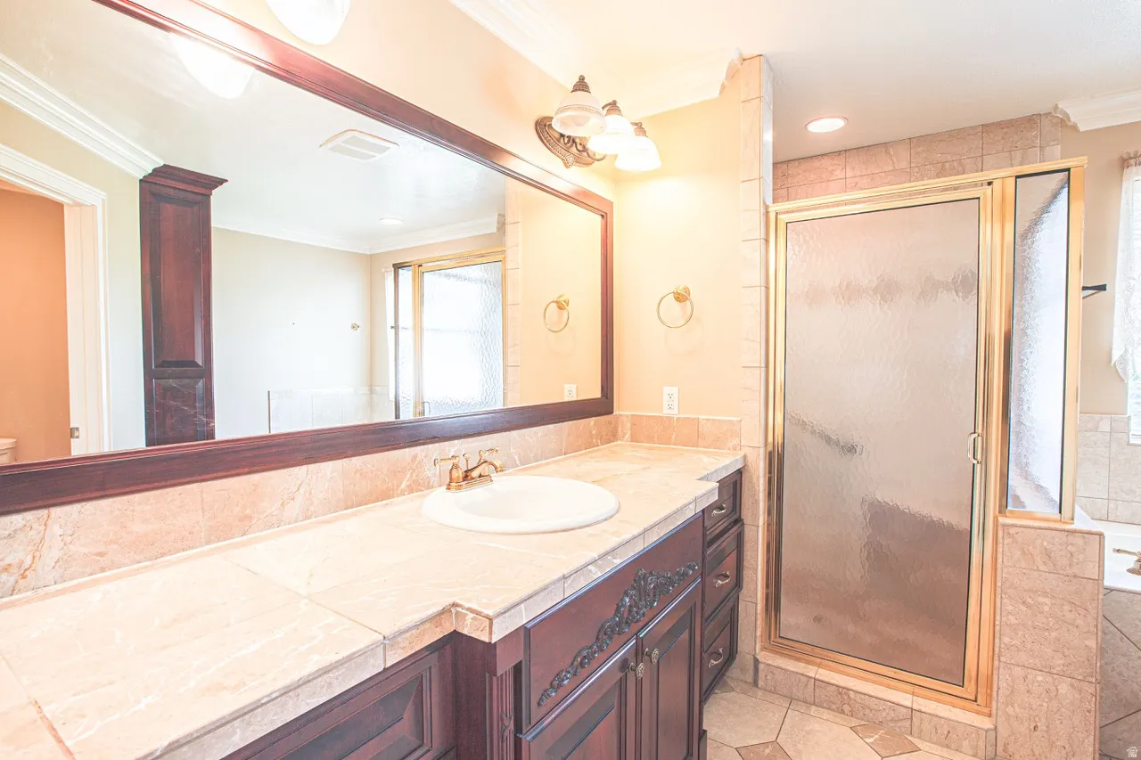 Bathroom featuring a vanity with a tile countertop, integrated sink, and an ornate dark wood-finish cabinet