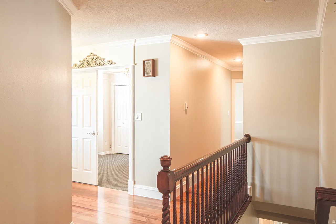 Upper-level hallway featuring wood-finish flooring, white trim, recessed lighting, and a dark wood banister