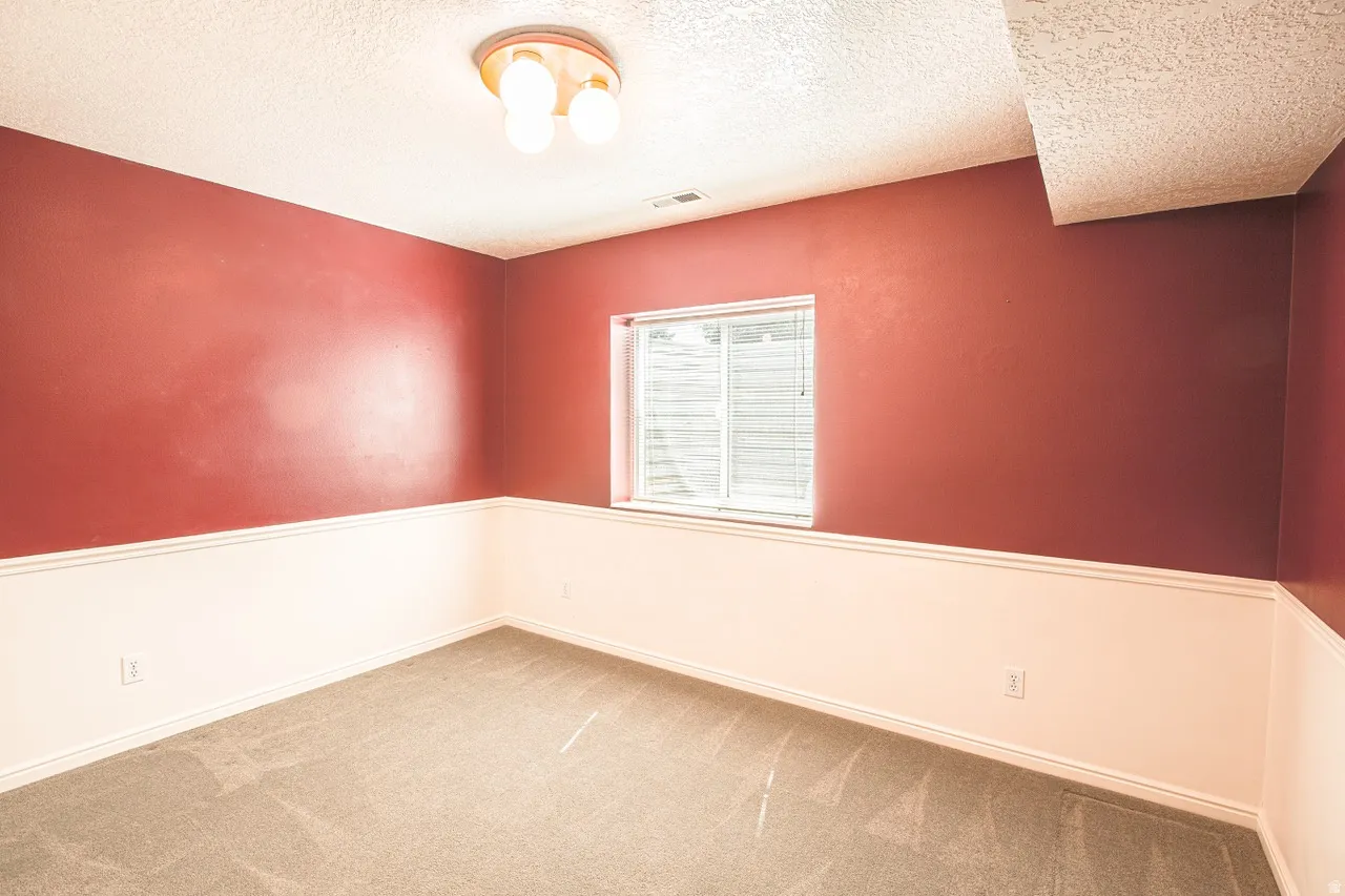 Carpeted room featuring a white-framed window with blinds, red and white two-tone walls, white trim, and a semi-flush ceiling light fixture