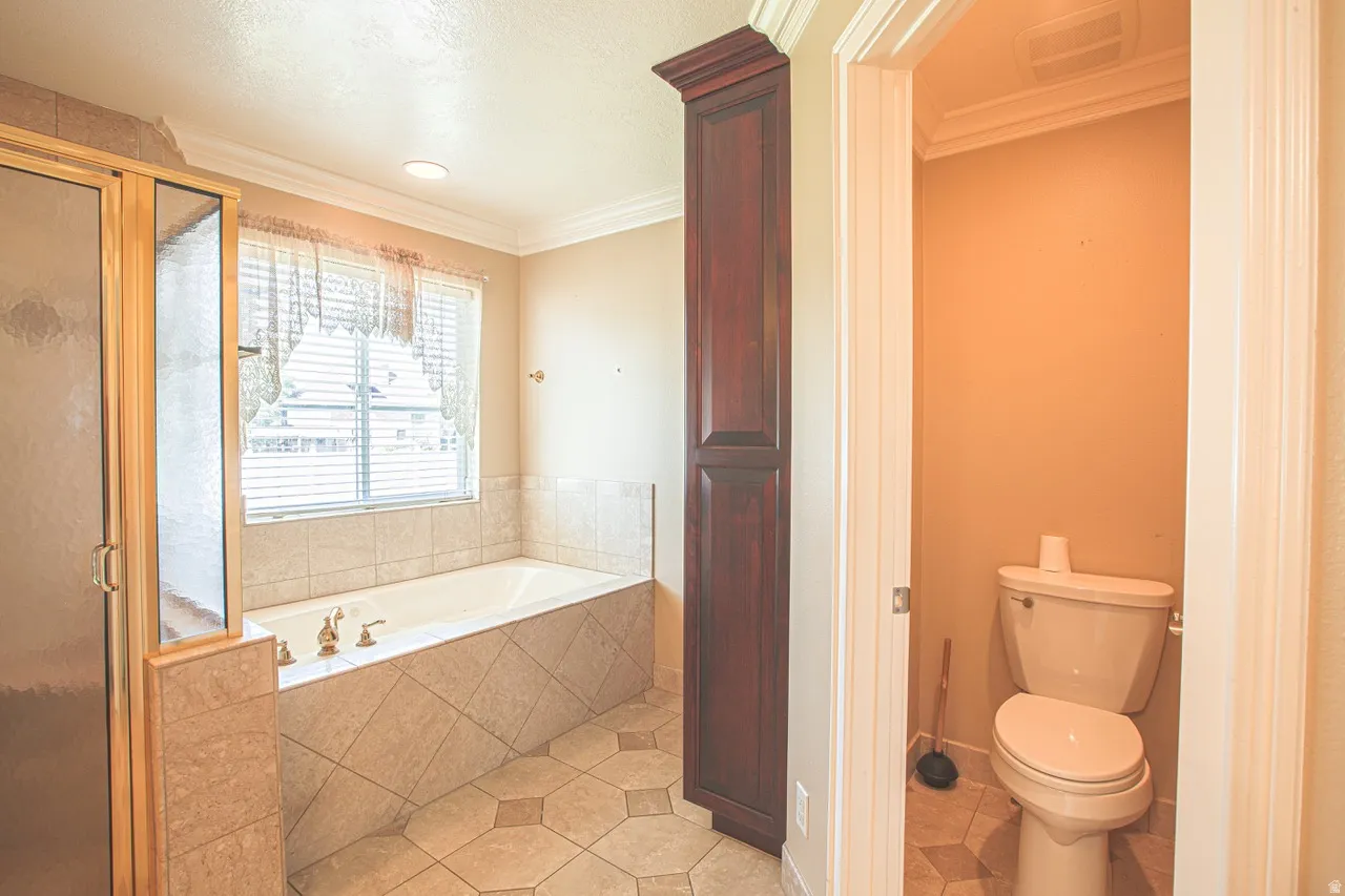 Bathroom featuring a built-in soaking tub with brass fixtures, a separate glass-enclosed shower, dark wood-finish built-in cabinetry, and tile flooring