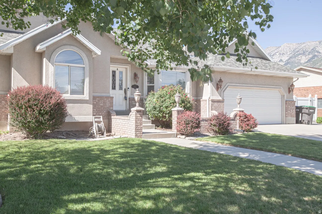 Exterior featuring a stucco facade, brick accents, arched window, and a two-car garage