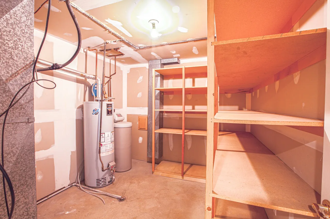 Utility area featuring a water heater, water softener, and extensive built-in wooden shelving for storage