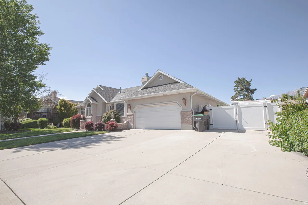 Property exterior featuring a concrete driveway, attached garage, and a white privacy fence