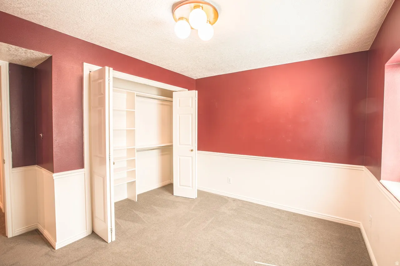 Bedroom featuring a built-in closet with shelves and hanging rods, two-tone wall treatment, textured ceiling, and a flush-mount ceiling light fixture