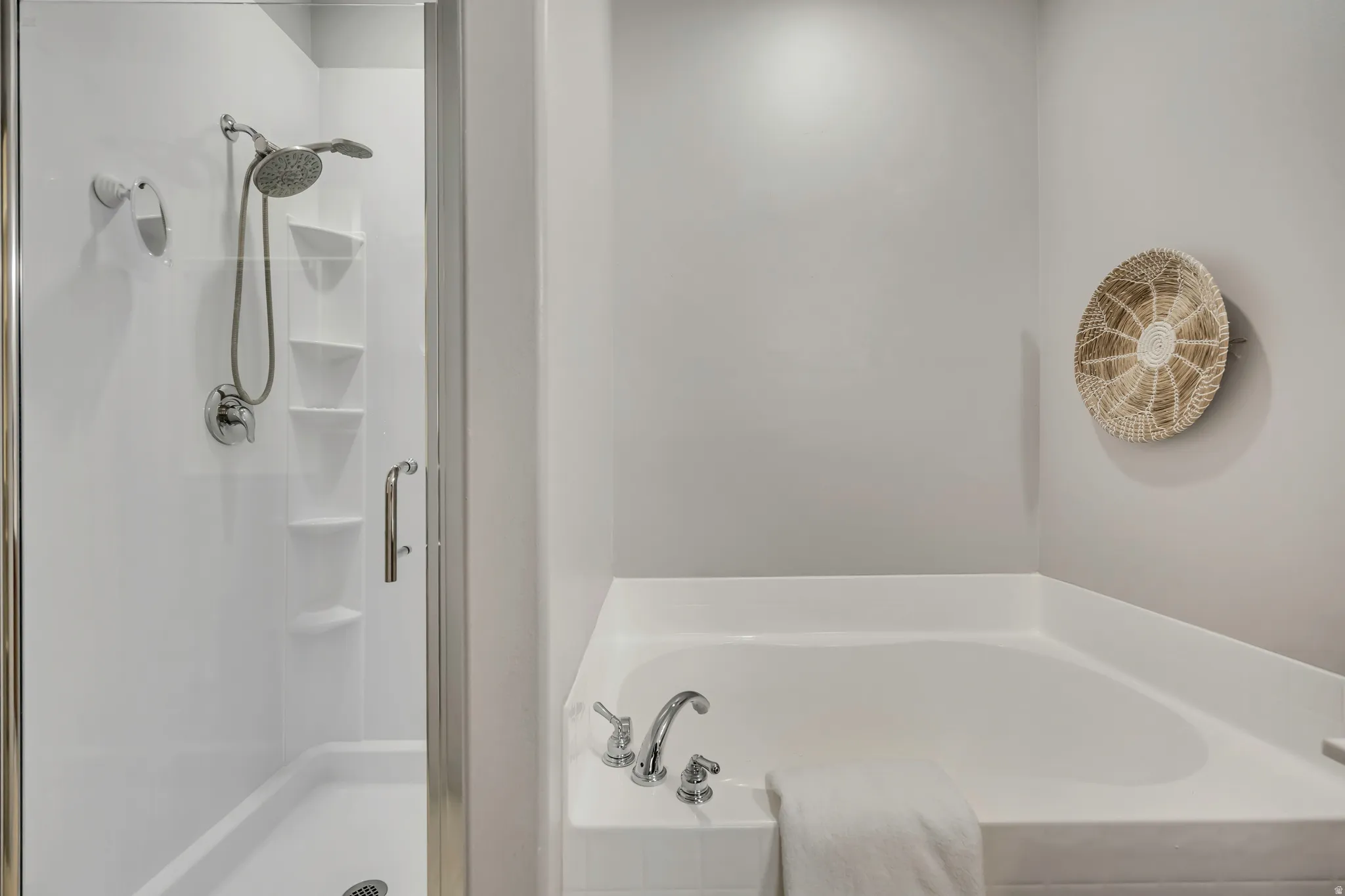 Shower with clear glass enclosure and built-in shelving, chrome fixtures, and an adjacent soaking tub with deck-mounted faucet