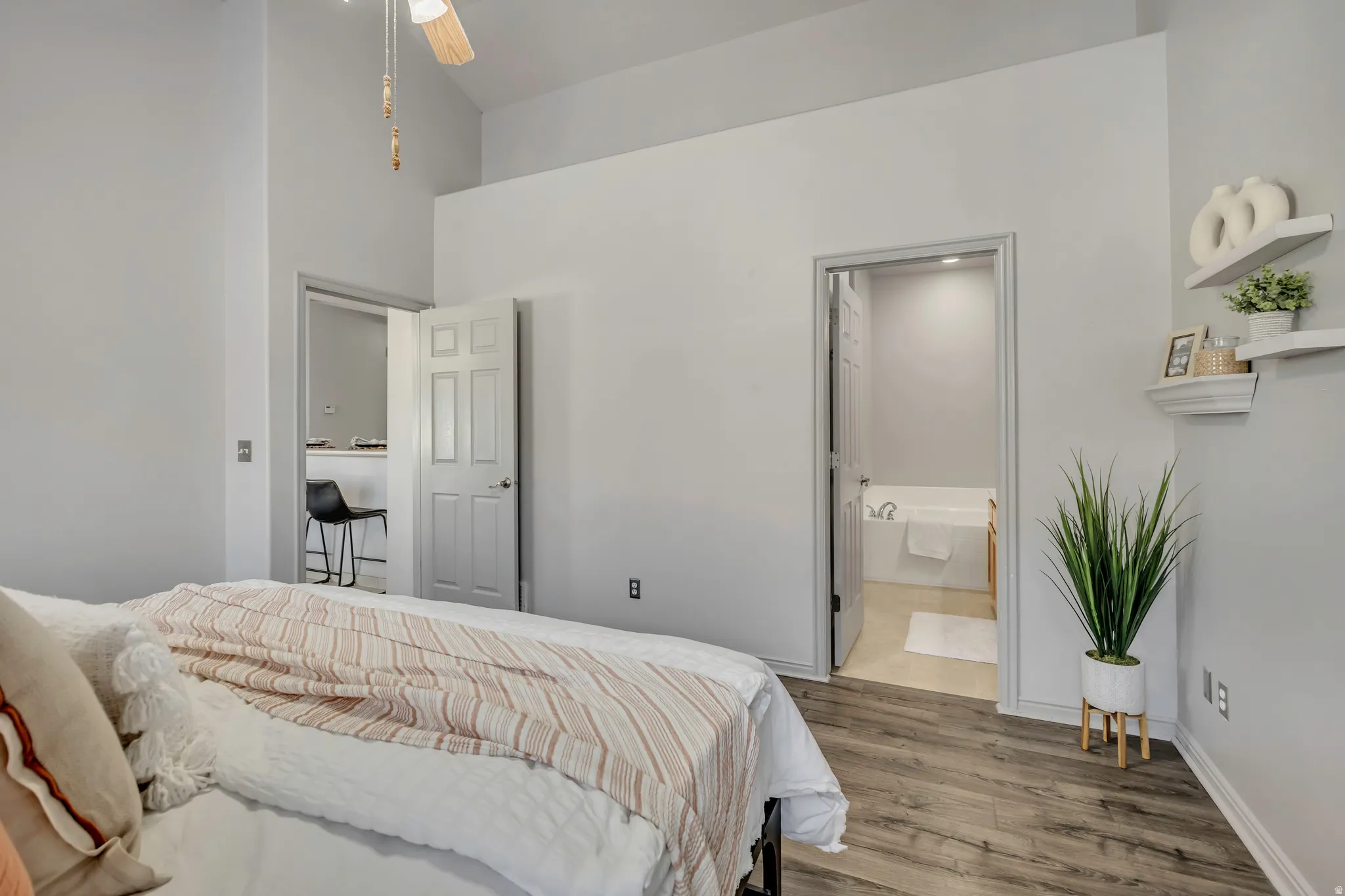 Room featuring wood-finish flooring, vaulted ceiling, and a ceiling fan with light fixture