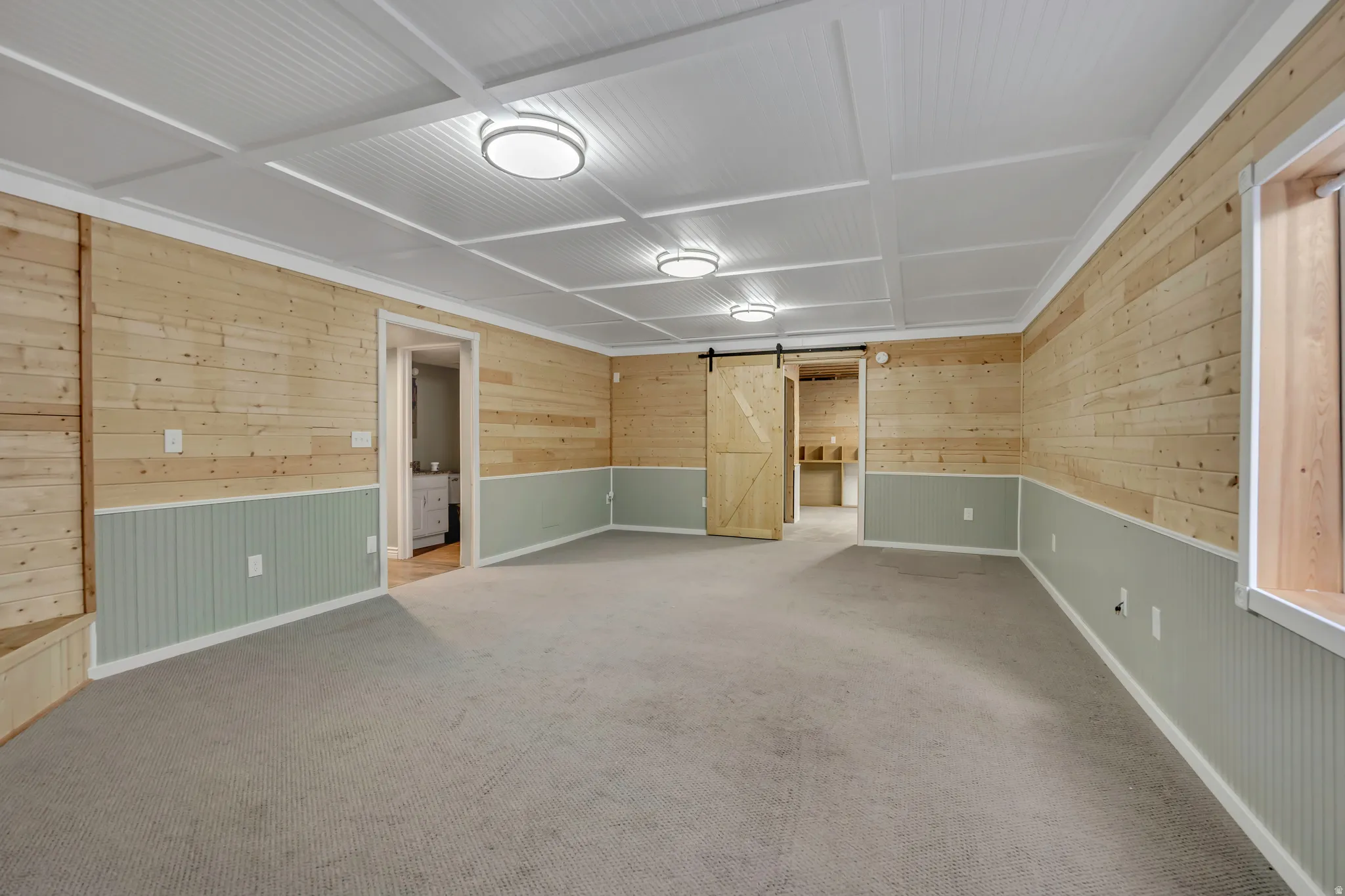 Spacious room featuring light wood plank walls over beadboard wainscoting, a box beam ceiling, and recessed lighting