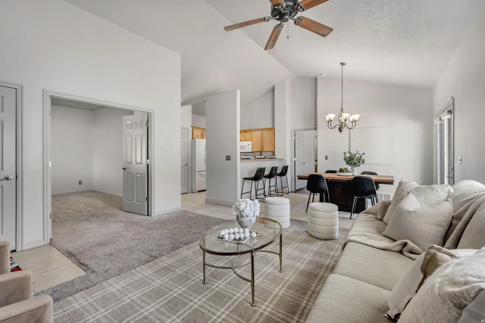 Open-concept living area featuring vaulted ceilings, a ceiling fan, and a chandelier