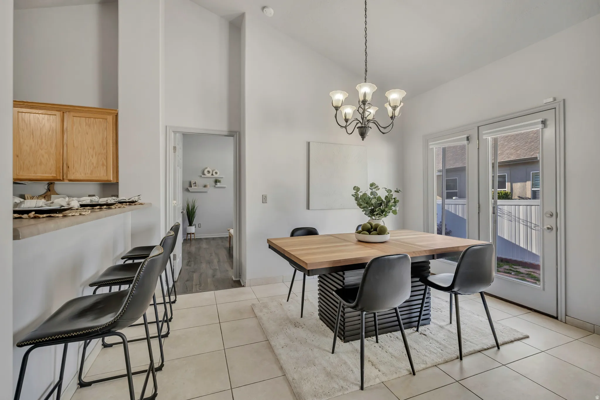 Open dining area featuring high vaulted ceilings, tile flooring, a breakfast bar, and double patio doors