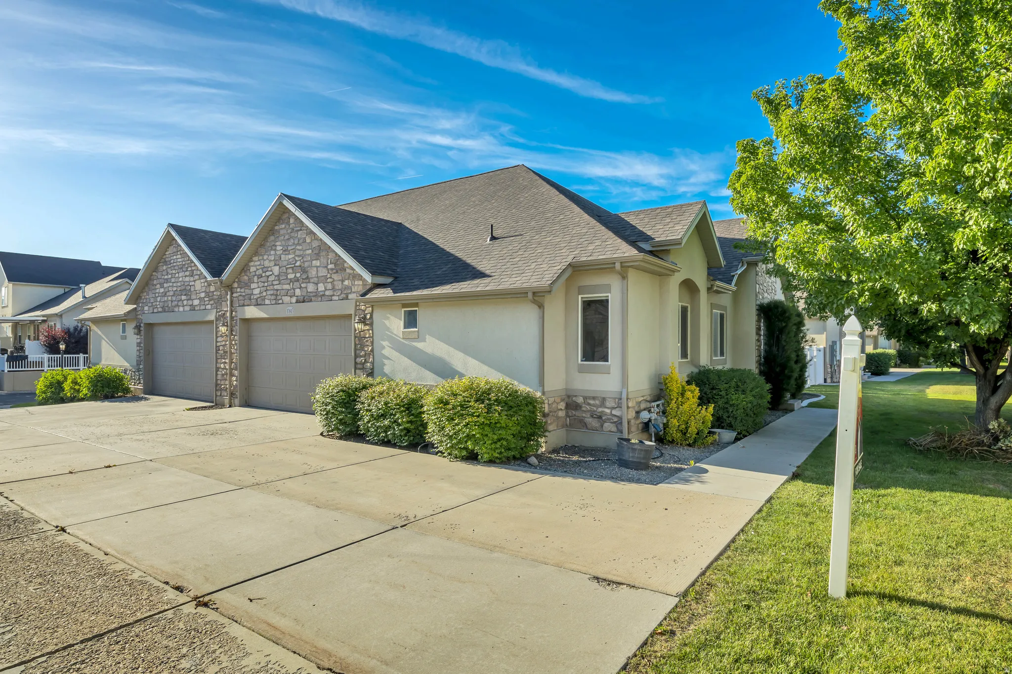 Stucco and stone exterior with two attached garages and a concrete driveway