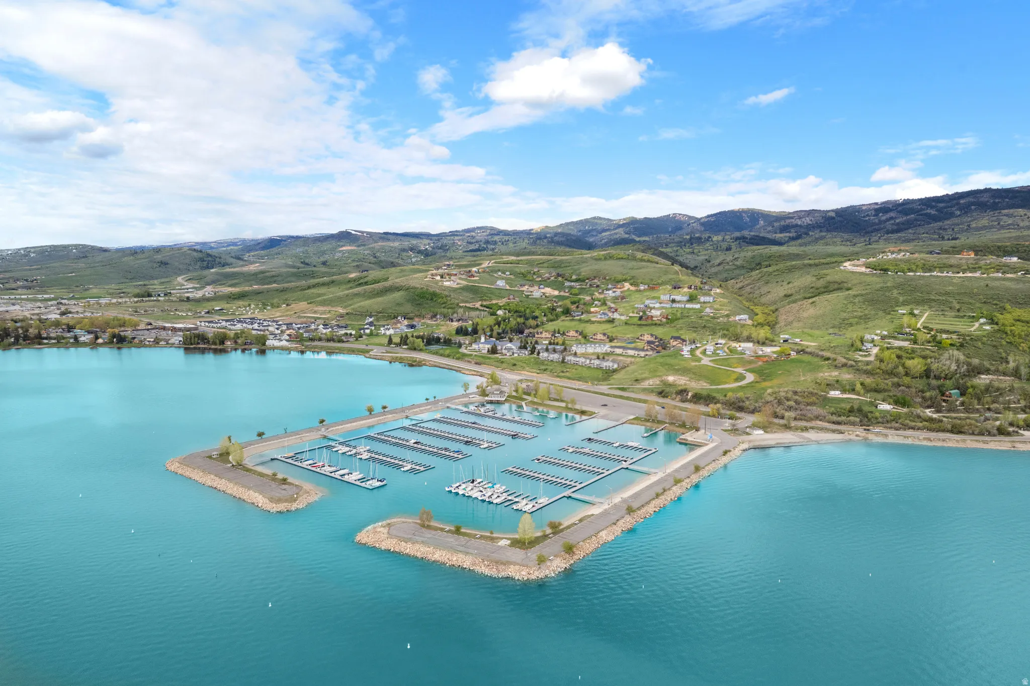 Expansive marina with numerous boat slips, set against a backdrop of rolling hills and a vibrant blue lake