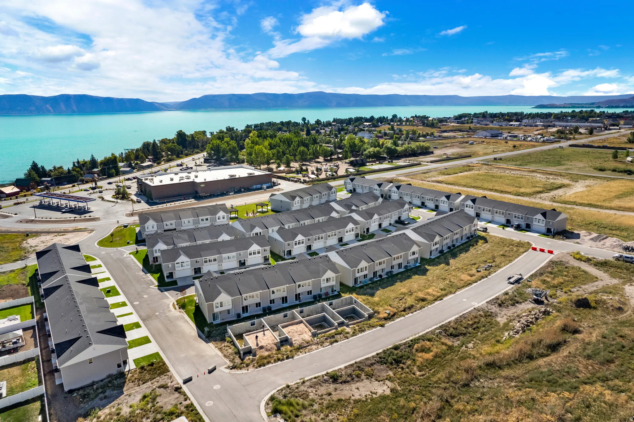 Aerial perspective showcasing a community of newly constructed multi-story townhomes with light-colored siding and dark roofs