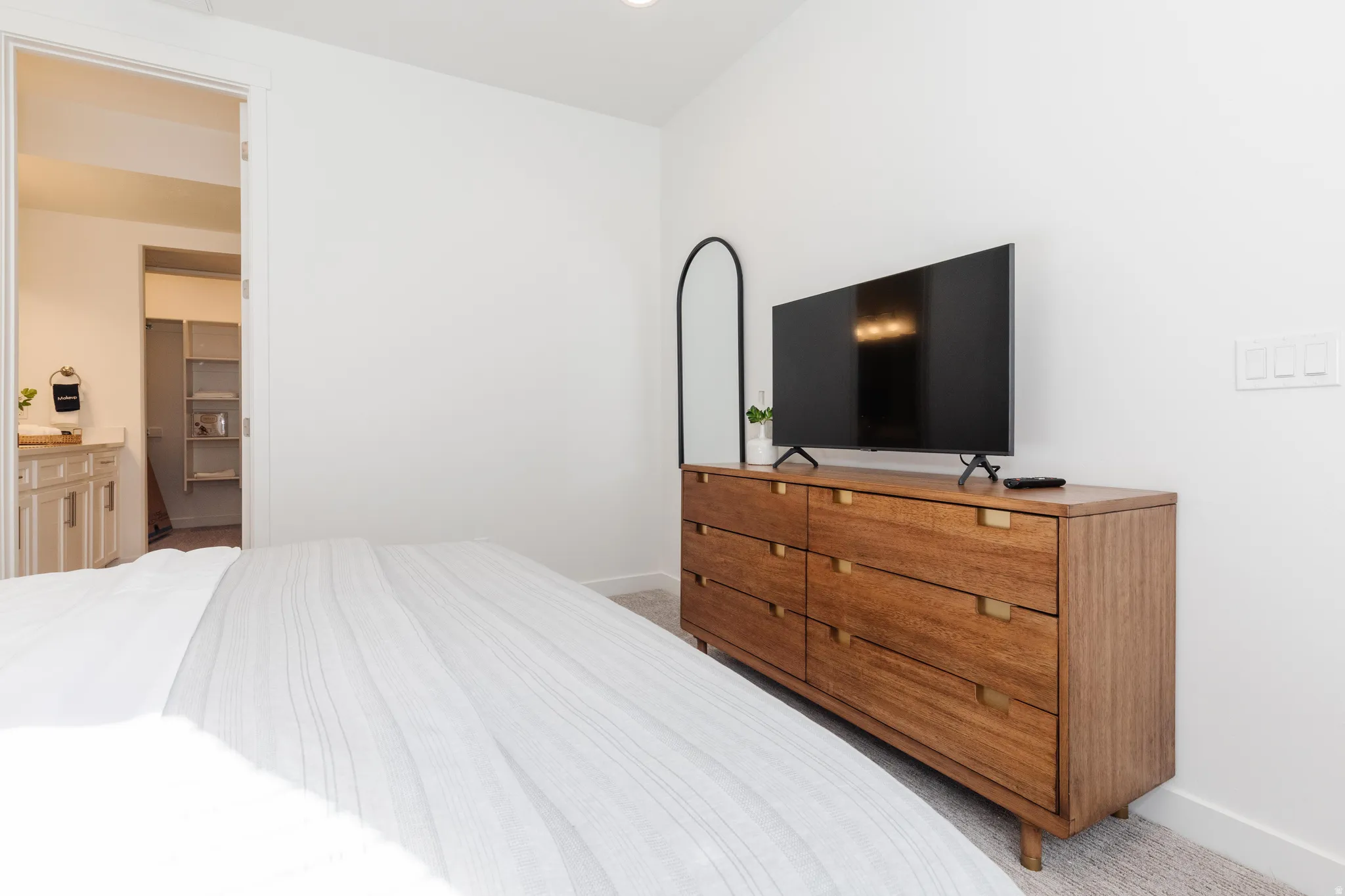 White-painted bedroom featuring a doorway to an adjacent walk-in closet with built-in shelving