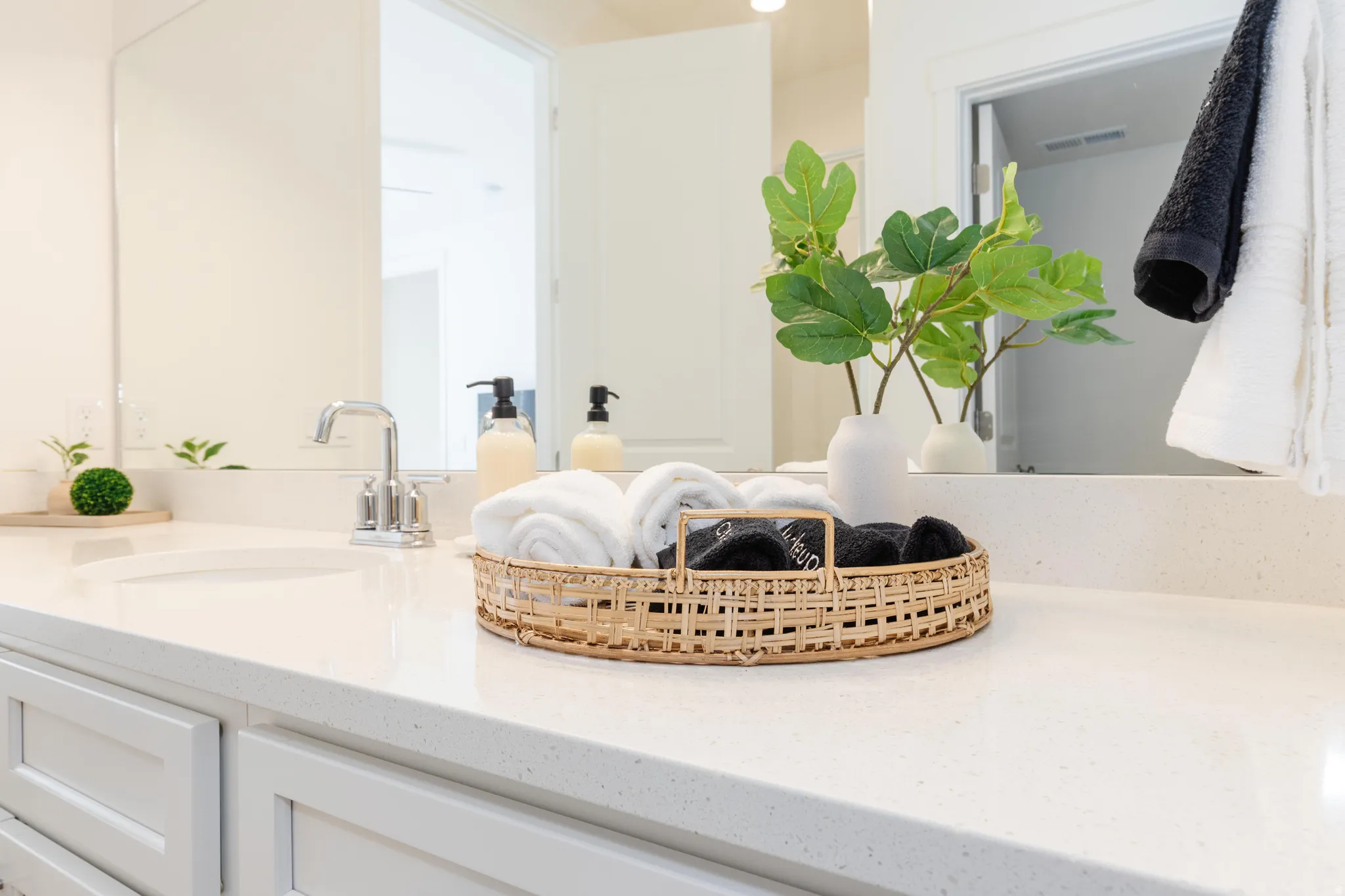 Vanity featuring a polished chrome faucet, under-mount sink, and light-toned solid surface countertop