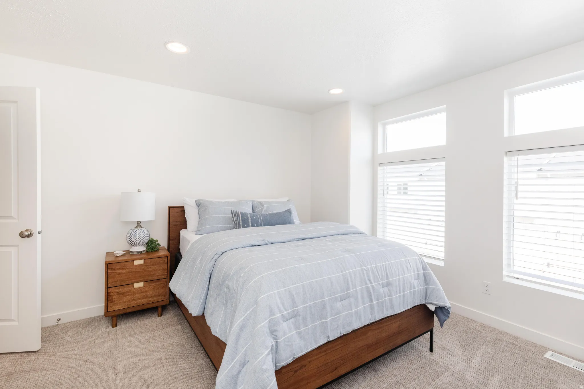 Bedroom featuring neutral carpeting, white walls, multiple windows with blinds, recessed lighting, and a white interior door