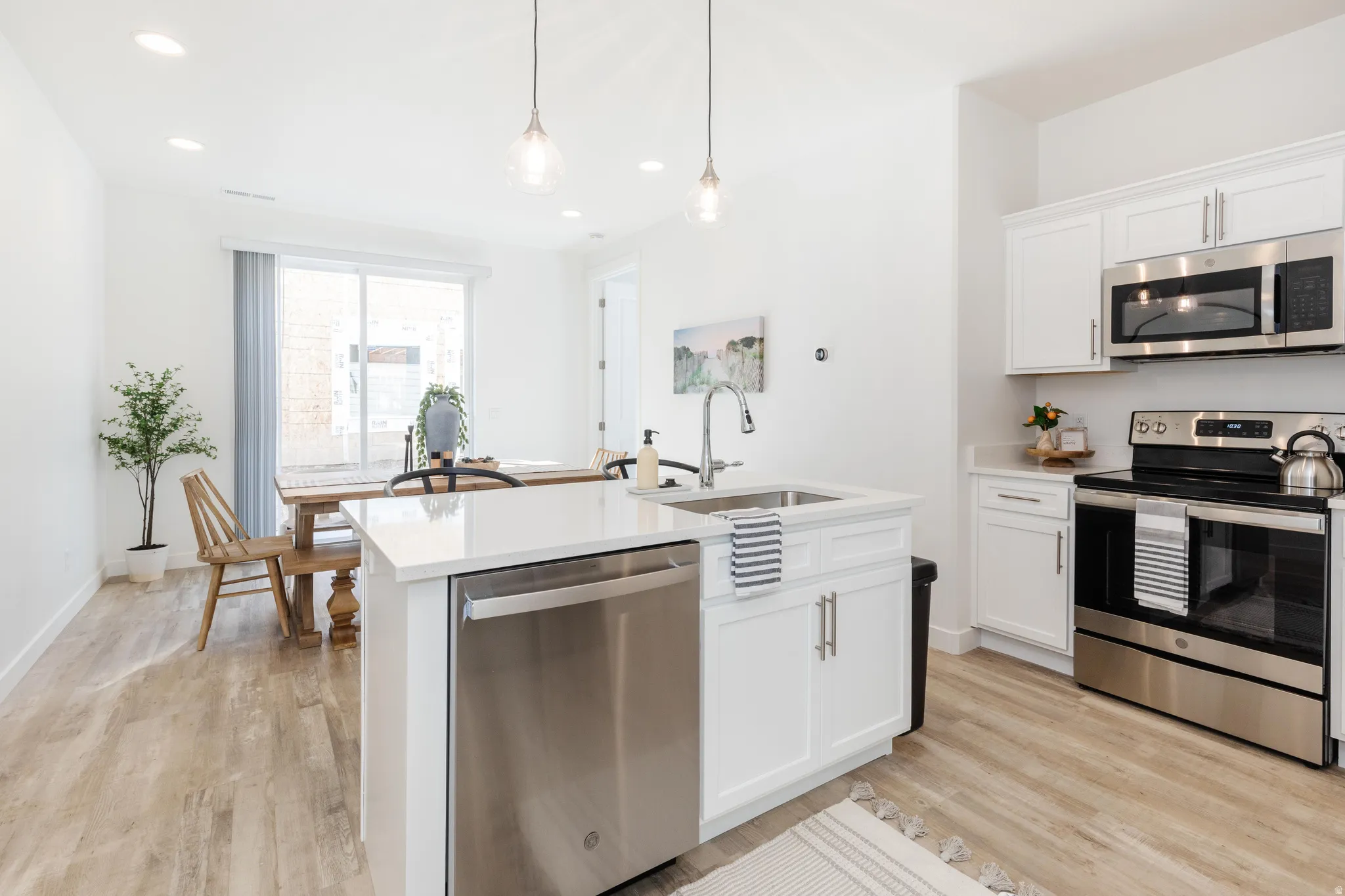 Modern kitchen featuring white cabinetry, stainless steel appliances, and a central island with an integrated sink and dishwasher