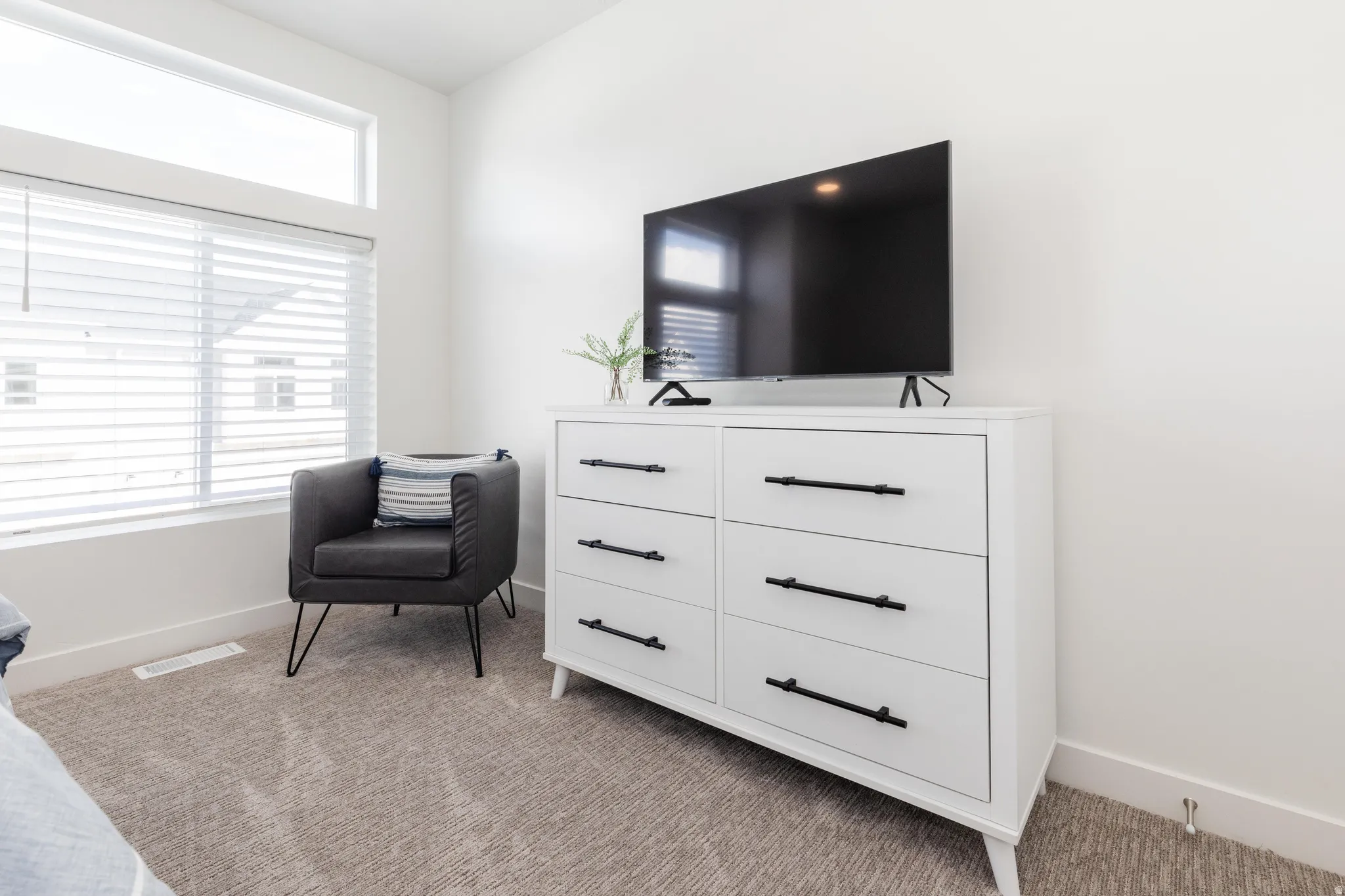 Plush carpeting, a large window with blinds, and an upper transom window