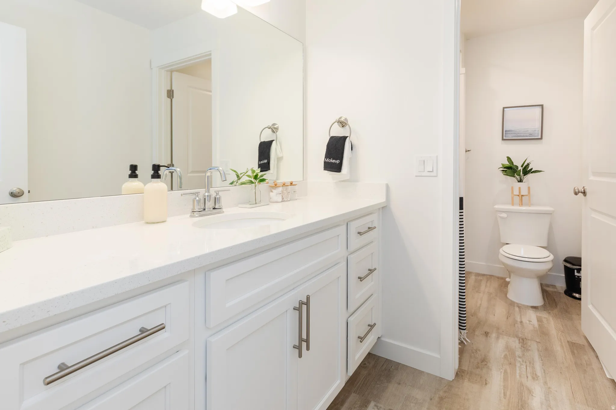 White vanity with a solid surface countertop and integrated sink, brushed nickel faucet, and a large wall-mounted mirror