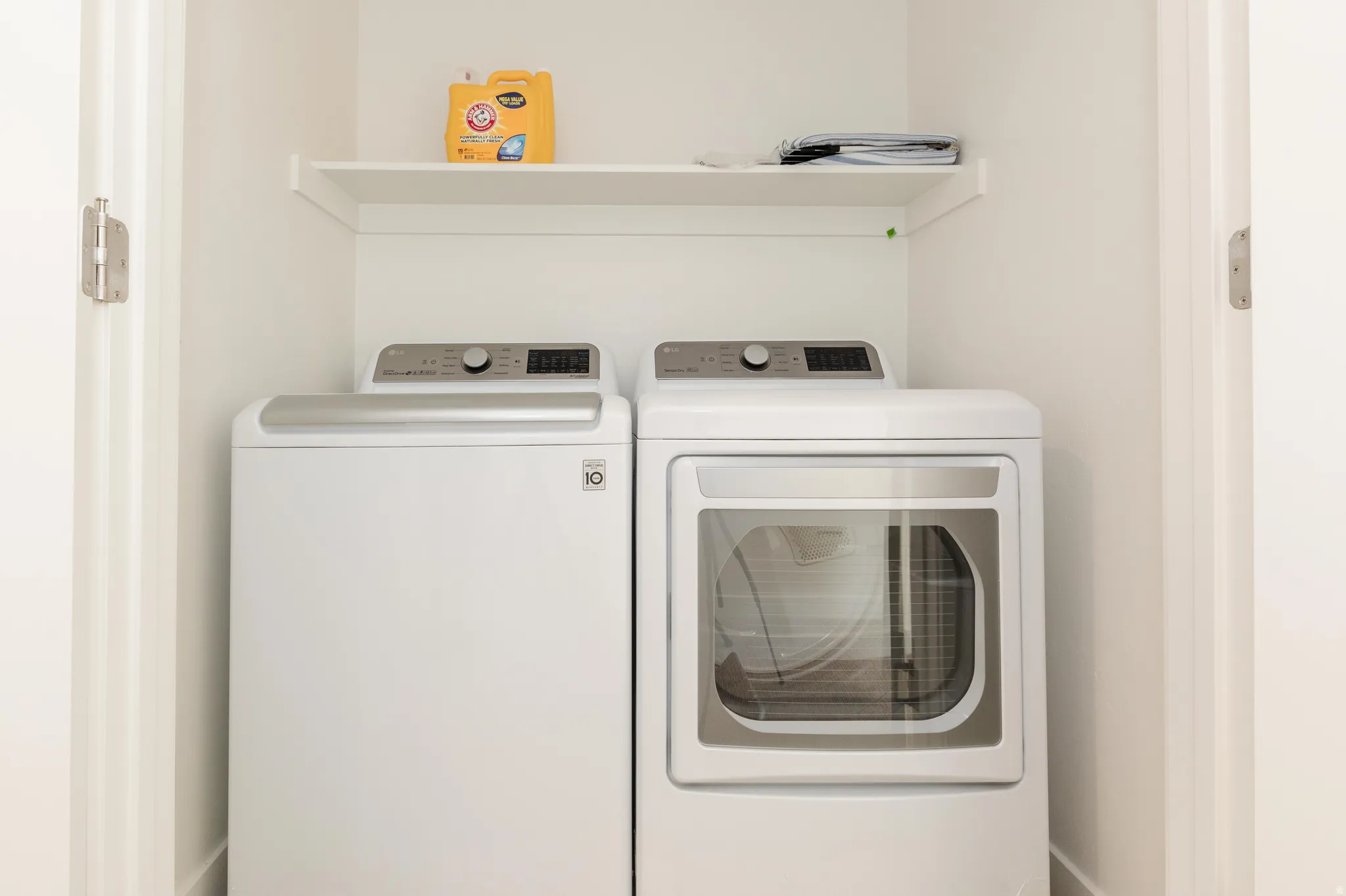 Dedicated laundry area featuring a white washer and dryer, complemented by an overhead storage shelf