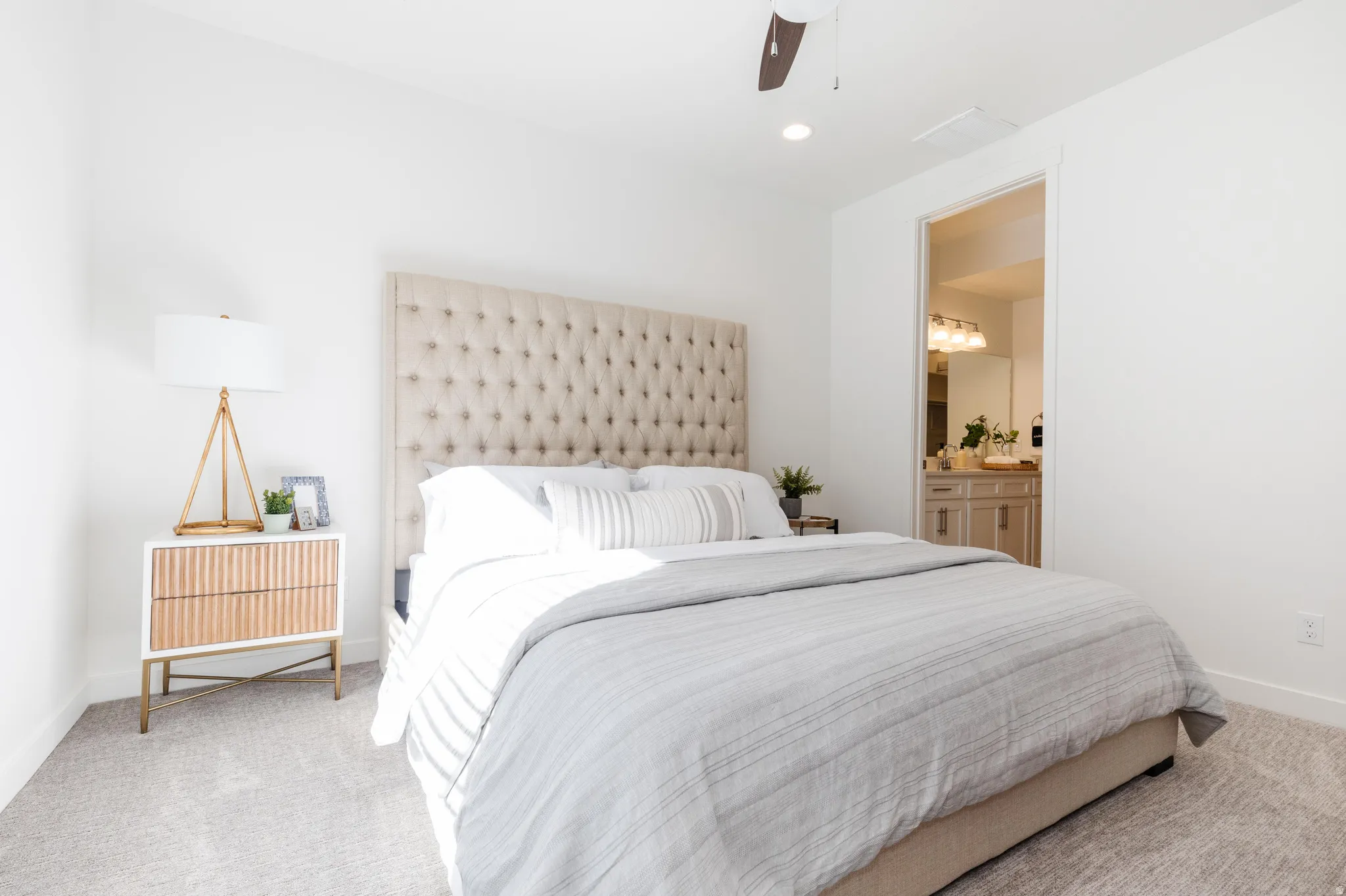 Bedroom featuring a tufted upholstered headboard, recessed lighting, and soft gray carpeting