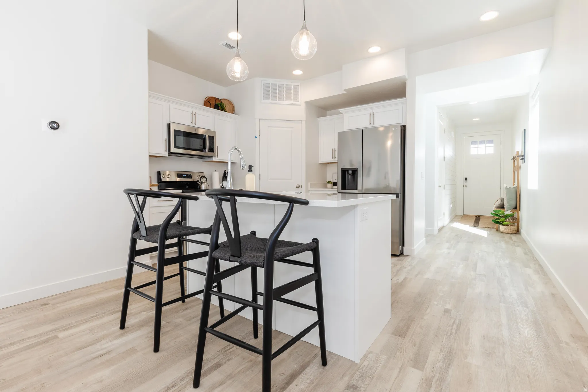 Kitchen featuring a central island with countertop seating, white cabinetry, stainless steel appliances, and integrated recessed lighting