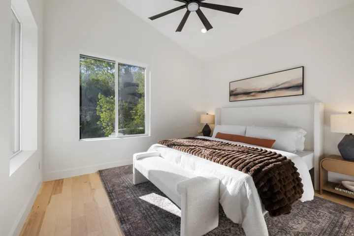 Vaulted ceiling, ceiling fan, natural wood-finish flooring, large window, and secondary window