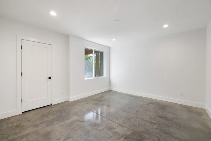 Polished concrete flooring, recessed lighting, white walls, white trim, and a horizontal window