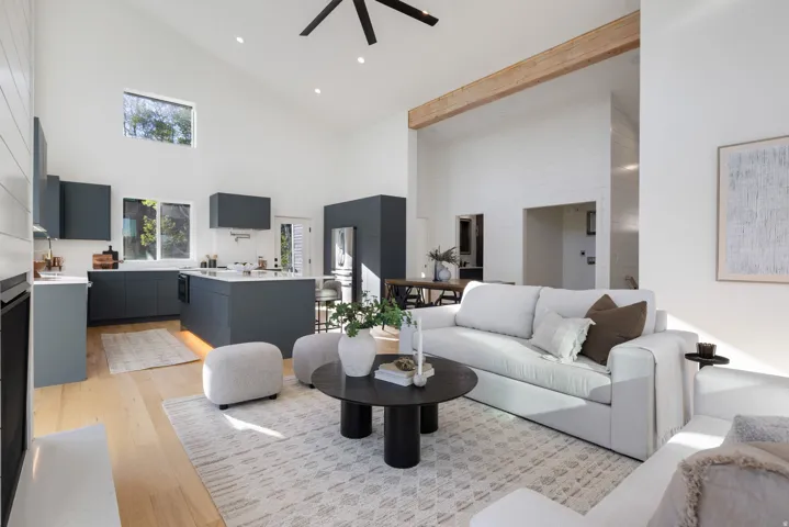 Vaulted ceilings with exposed wood beam, contemporary kitchen featuring dark cabinetry and white countertops, wood-finish flooring, and recessed lighting