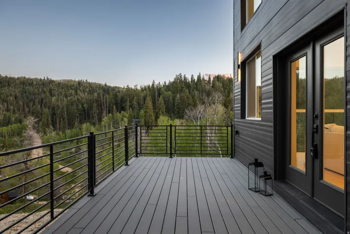 Expansive outdoor deck with composite decking, black metal railings, and dual exterior wall sconces
