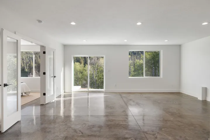 Polished concrete flooring, recessed lighting, white walls, double glass-paneled doors, and a sliding glass door