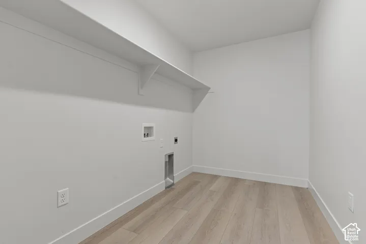 Laundry area with wood-finish flooring, white walls, and a built-in shelf
