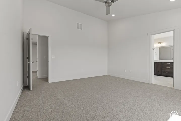 Spacious room featuring vaulted ceilings, light-toned carpeting, and recessed lighting