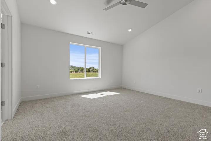 Spacious room featuring neutral carpeting, recessed lighting, a contemporary ceiling fan, and a large window offering outdoor scenery