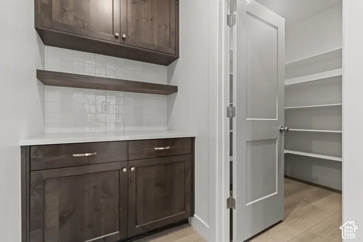 Dark wood-finish cabinetry with silver hardware, white countertop, and white square tile backsplash