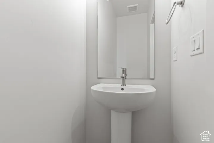 Pedestal sink with a modern faucet and a rectangular wall mirror